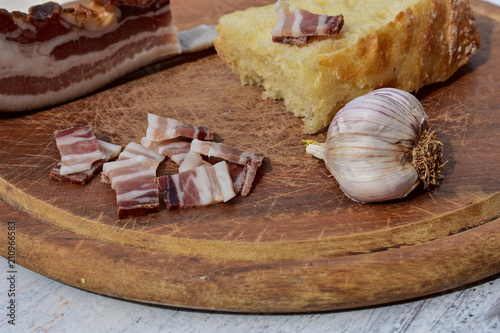 Delicious plate with smoked bacon, garlic and bread at rustic wooden background/ Traditional Balkan food