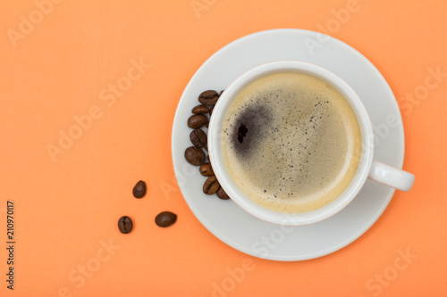 Cup of coffee and coffee beans on peach background