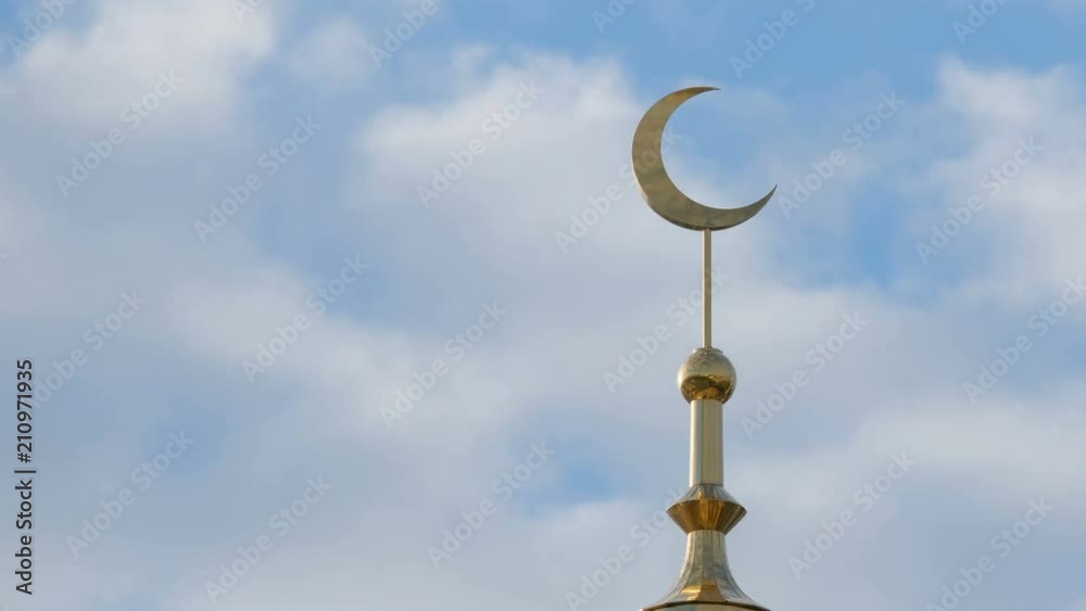 A golden crescent on the minaret of the Moslem mosque against the sky with rapidly moving clouds in the right corner of the frame. Close up. Time Lapse. A golden crescent on the minaret of the Moslem mosque against the sky with rapidly moving clouds in the right corner of the frame. Close up. Time Lapse.