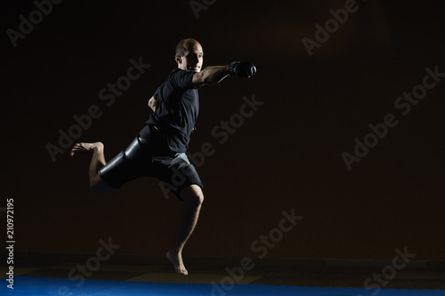 Athlete jumping over blue tatami beats with a hand © andreyfire