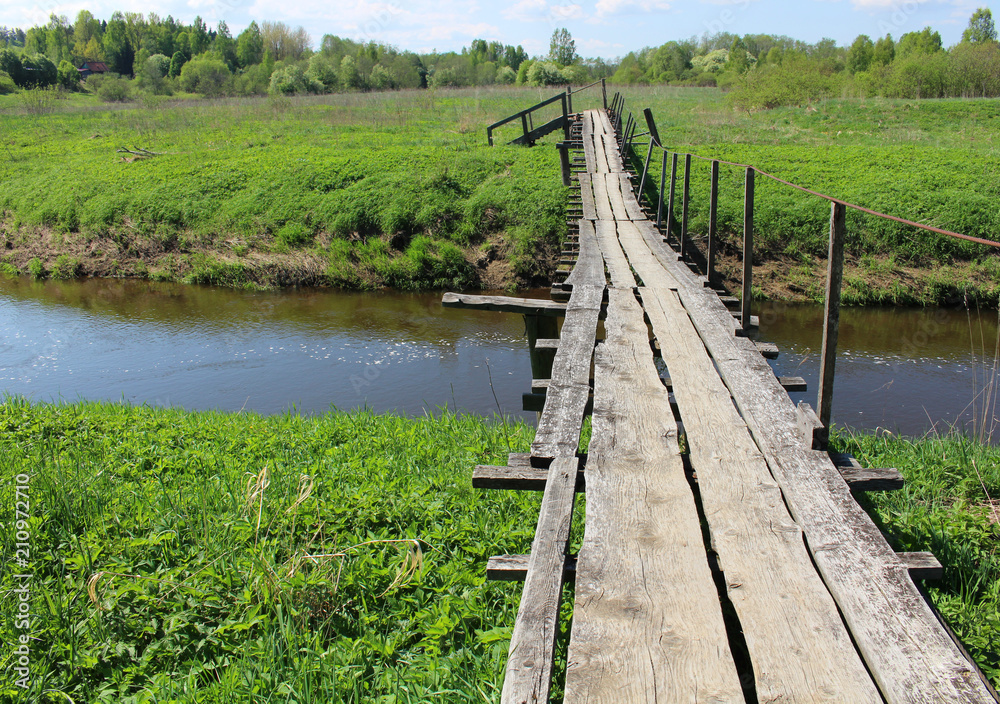 Fototapeta premium Old wooden bridge over river in summer countryside