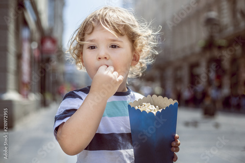 Little boy eating popcorn in the city