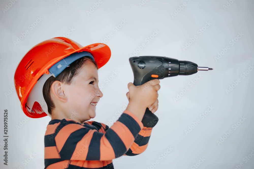 little builder in the helmet with a drill and saw the work of thinking about the future