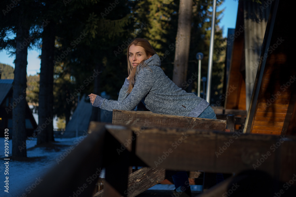 Beautiful woman with white cup standing on terrace of wooden house and smiling Beautiful woman with white cup standing on terrace of wooden house and smiling