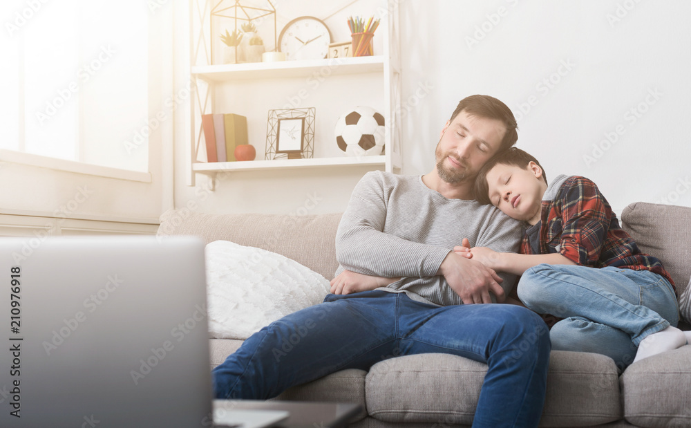 Tired father and son sleeping on sofa at home