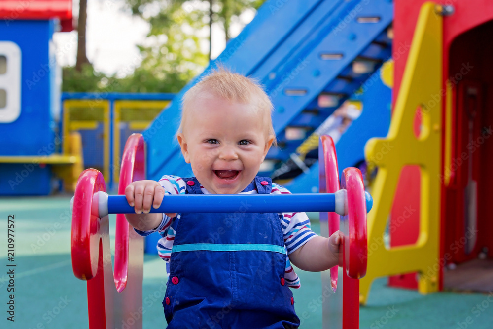 Adorable little 1-2 year old toddler boy having fun on playground, child playing Adorable little 1-2 year old toddler boy having fun on playground, child playing
