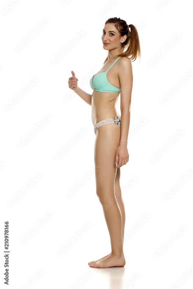 Young pretty woman in bikini on white background showing thumbs up Young pretty woman in bikini on white background showing thumbs up