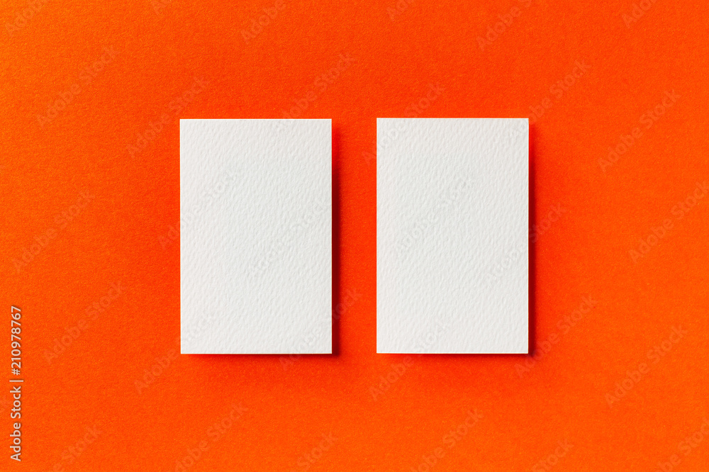 Mock up of two vertical white blank business cards isolated at orange paper background. Mock up of two vertical white blank business cards isolated at orange paper background.