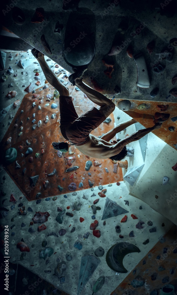 Free climber young man climbing artificial boulder indoors Free climber young man climbing artificial boulder indoors
