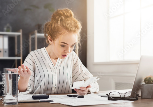 Shocked business woman looking at increasing costs photo