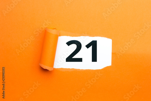 Zahl einundzwanzig - 21 verdeckt unter aufgerissenem orangen Papier