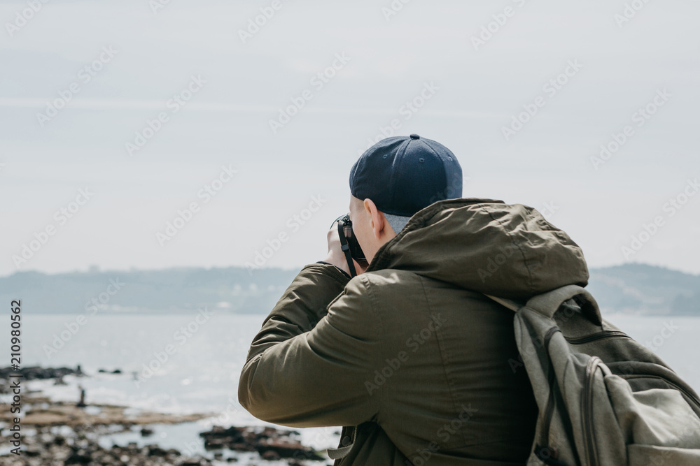 A professional photographer or a tourist man photographs a beautiful view of the sea in Lisbon in Portugal