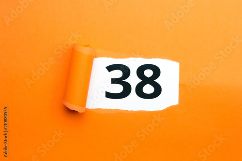 Zahl achtunddreißig - 38 verdeckt unter aufgerissenem orangen Papier