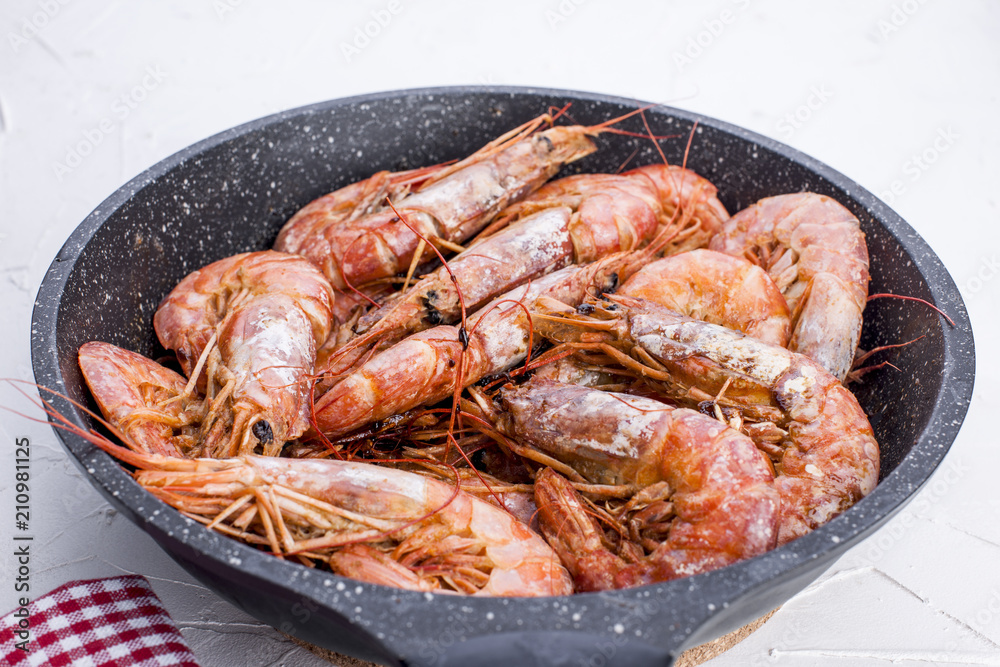 Large shrimps fried in a frying pan. On a white table. Lunch from seafood. Free space for text. Copy space, Large shrimps fried in a frying pan. On a white table. Lunch from seafood. Free space for text. Copy space,