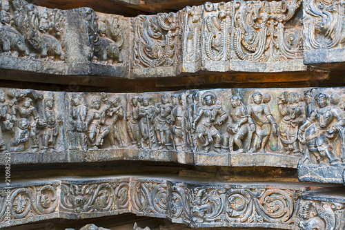 Friezes of animals, scenes from mythological episodes from Ramayana and Mahabharata, at the base of temple, Hoysaleshwara temple, Halebidu, Karnataka. View from North. photo