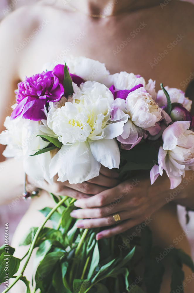 Sensual girl with bunch of colorful peony flowers in her hands