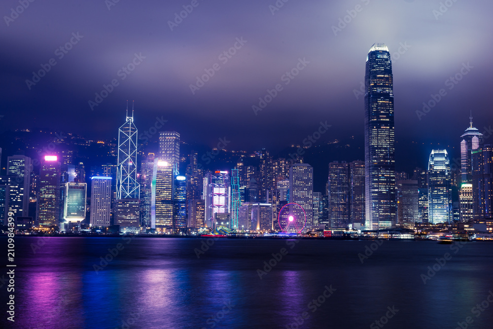 Hong Kong skyline on Victoria Harbour with moody mist and clouds in sky Hong Kong skyline on Victoria Harbour with moody mist and clouds in sky