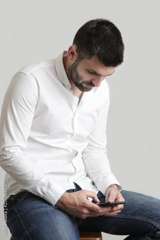 Studio portrait of young man typing message on his smart phone Studio portrait of young man typing message on his smart phone