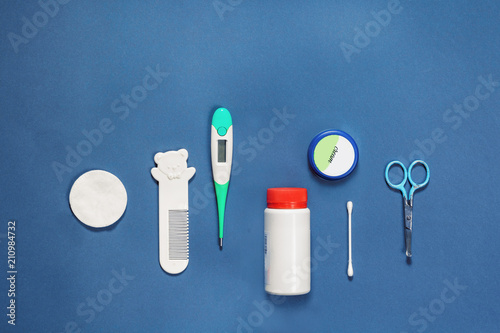 Accessory for the care of a newborn, scissors, comb, cream, powder, thermometer, stick, cotton wool, on a blue turquoise background, Flatlay photo