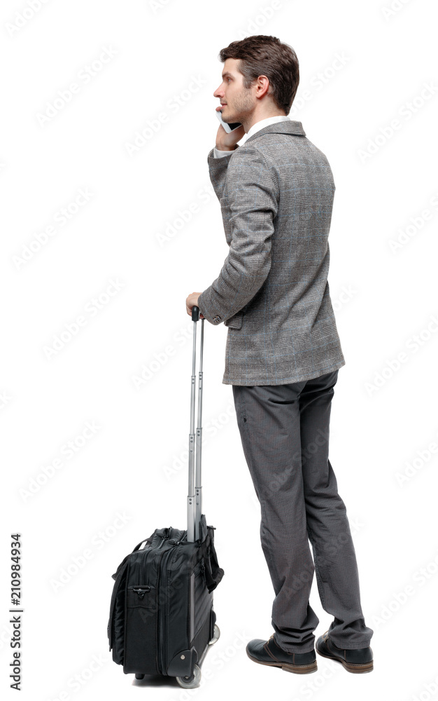 Back view of business man with suitcase talking on the phone. Back view of business man with suitcase talking on the phone.