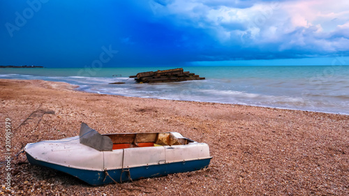 The sky is dramatic before the storm. The boat on the beach