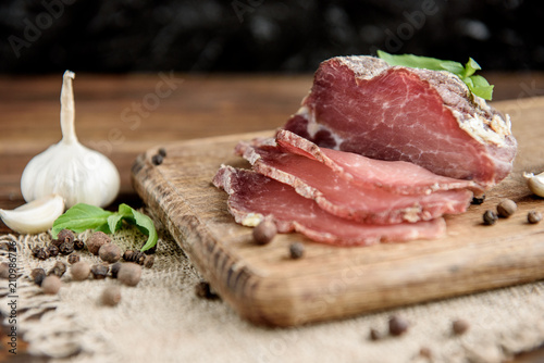 Bilde på lerret Pork dried meat slices on rustic dark wooden background