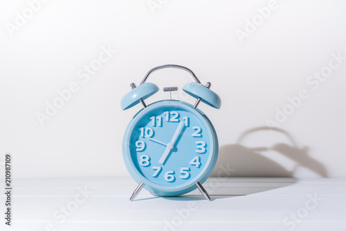 Blue analog alarm clock over white background.