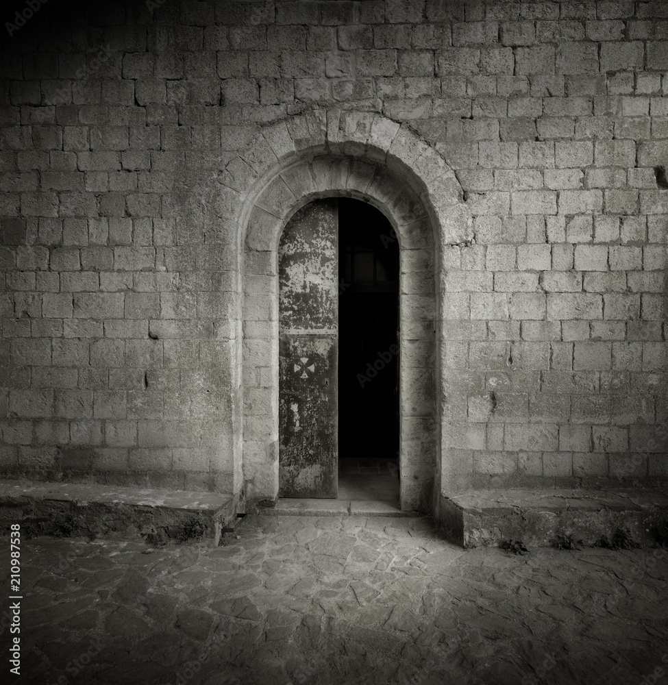Black and white photographic film shot of medieval gate. Castle entrance door.