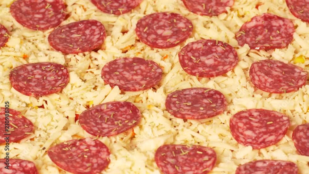 UHD closeup shot of the unbaked pepperoni pizza on a rotating stand UHD closeup shot of the unbaked pepperoni pizza on a rotating stand