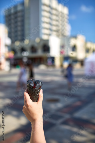 A first person view, girl walking along the road with an ice cream in her hands, shallow depth of field.