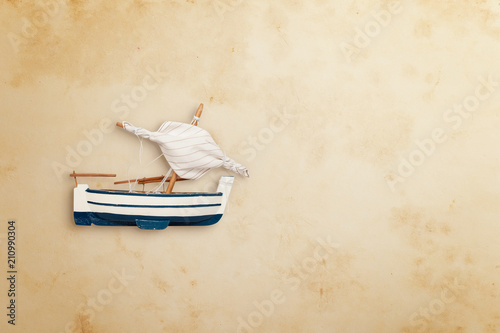 Fototapeta Naklejka Na Ścianę i Meble -  Top view of sailboat toy on old yellow paper. Flat lay. Travel concept, empty space for text