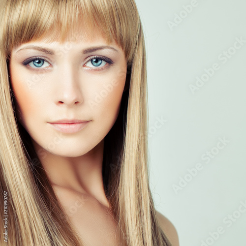 Young blonde woman face closeup. Female model with blonde hair on background