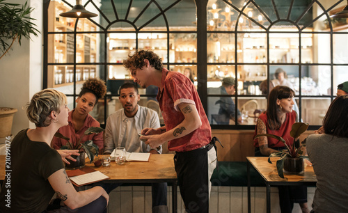 Waiter taking orders from customers sitting in a bistro