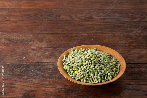 Nutritious green peas in a bowl and plate on rustic wooden background, close-up, top view, selective focus.