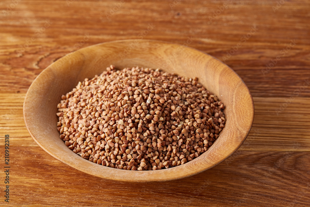 Bowl full of buckwheat grains on rustic wooden table, close-up, selective focus, shallow depth of field. Bowl full of buckwheat grains on rustic wooden table, close-up, selective focus, shallow depth of field.