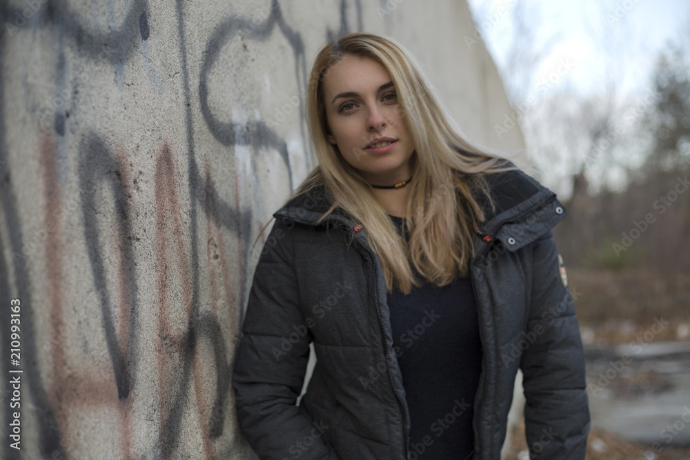 Fototapeta premium Beautiful woman with blonde hair walking on road in forest and looking at camera