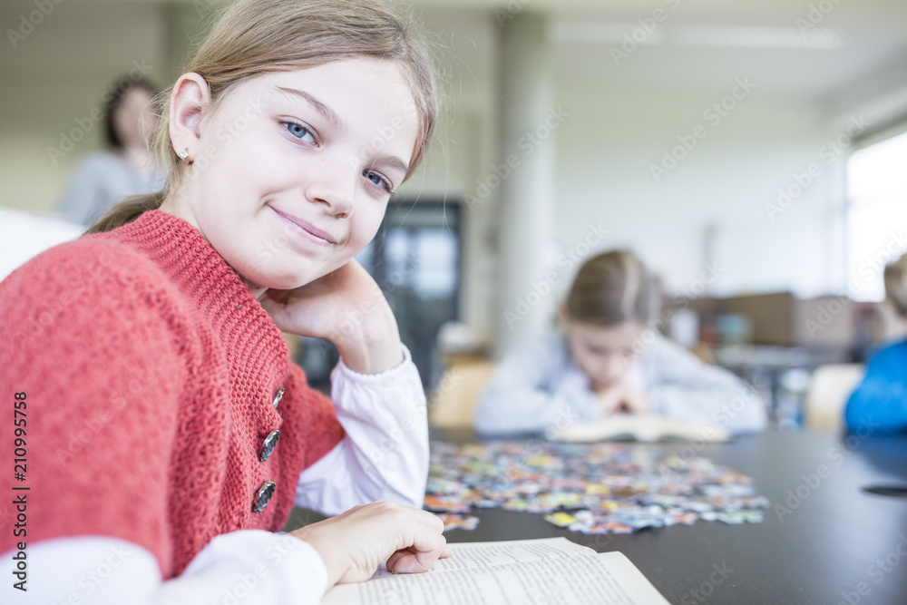 Portrait of smiling schoolgirl with book in school break room Portrait of smiling schoolgirl with book in school break room