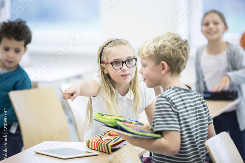 Serious girl rebuking boy in class photo