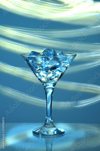  a martini glass with ice cubes on a blue background photo