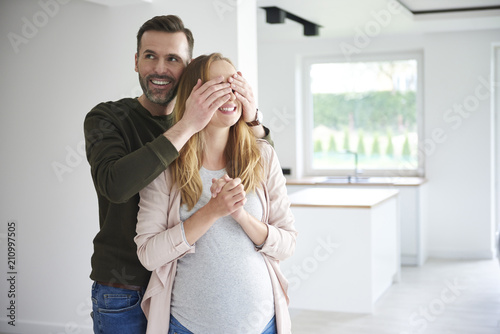 Man surprising pregnant woman in empty flat