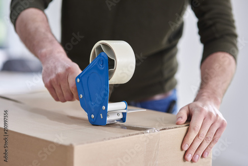 Close-up of man taping cardboard box photo