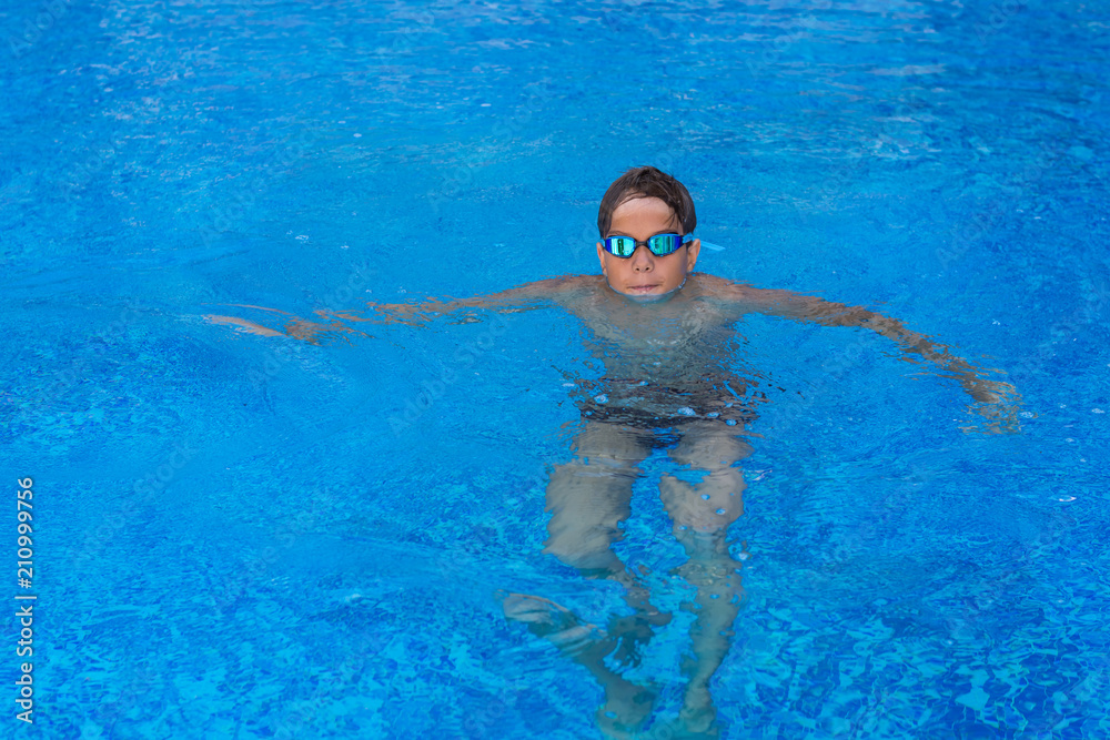 Portrait of a boy, athlete with swimming goggles in pool.