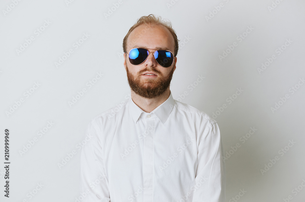 Serios fashionable young hipster bearded man wearing sunglasses and a white shirt. Serios fashionable young hipster bearded man wearing sunglasses and a white shirt.
