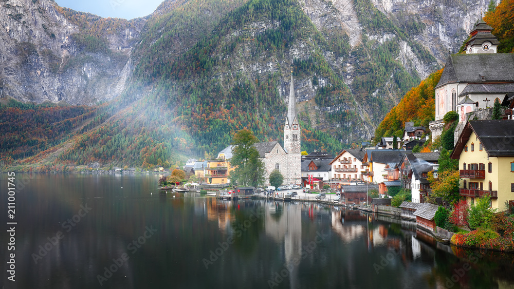 Scenic view of famous Hallstatt mountain village with Hallstatter lake See in beautiful golden morning light in fall