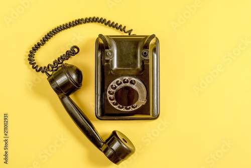 Vintage black telephone on yellow