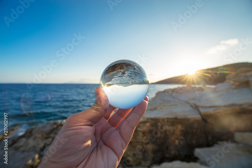 The seascape at sunset is reflected in a glass