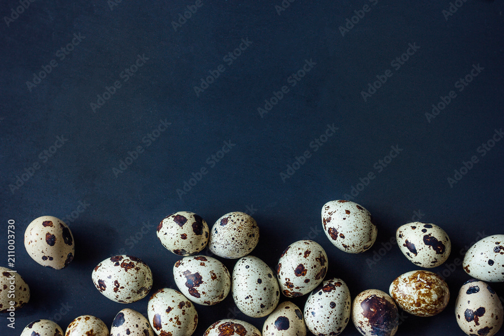 A lot of fresh quail eggs on black background. Eco-friendly farm product. With copy space for your text