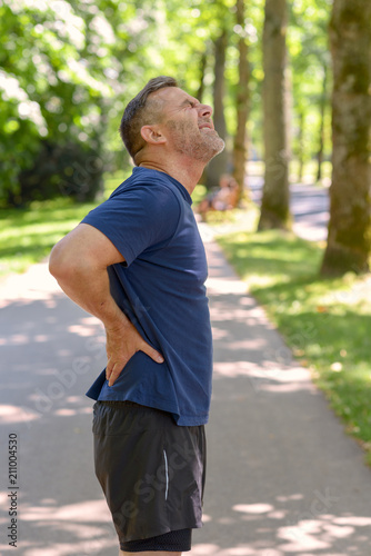 Mature man holding his painful back after running