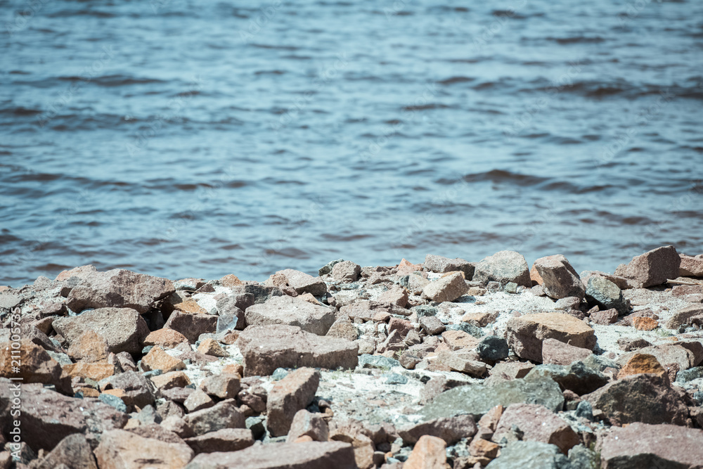 selective focus of rocky beach and wavy sea behind during daytime selective focus of rocky beach and wavy sea behind during daytime