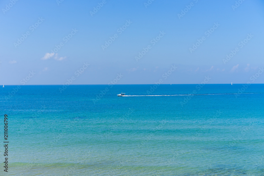 Calm water with a boat in the distance at the beach in Tel Aviv, Israel